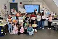 Die Kinder der Grundschule Gundelsheim zeigen ihre Bilder, mit denen sie den MPDV-Malwettbewerb gewonnen haben.