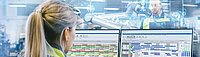 At the Factory: Female Mechanical Engineer Designs 3D Engine on Her Personal Computer. In the Background Male Automation Engineer who Uses Laptop for Programming Robotic Arm.