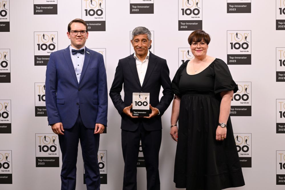 Ranga Yogeshwar (center), mentor of the TOP100 Innovation Competition, presents Nathalie Kletti (right), CEO MPDV, and Peter Hofmann (left), Innovation Manager MPDV, with the award for second place in the TOP100 Innovators in category C. 