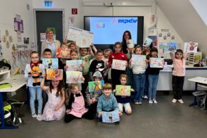 Die Kinder der Grundschule Gundelsheim zeigen ihre Bilder, mit denen sie den MPDV-Malwettbewerb gewonnen haben.